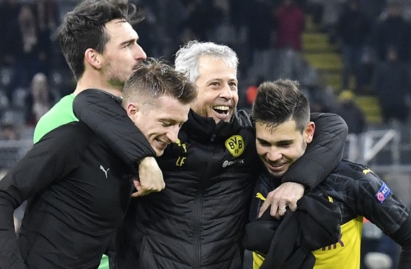 Dortmund&#039;s head coach Lucien Favre, center, embraces Dortmund&#039;s Marco Reus, left, and Dortmund&#039;s Raphael Guerreiro, right, after winning the Champions League Group F soccer match betwee ...