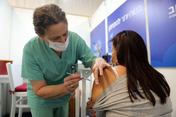 epa08912569 An Israeli woman receives a COVID-19 vaccine by a nurse in the new Tel Aviv municipality vaccines center in Rabin square, Tel Aviv, Israel, 31 December 2020. Media report that Israel is on ...