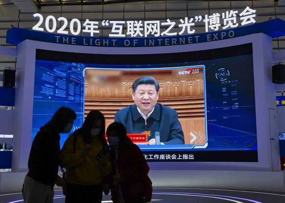 epa08837176 People stand in front of the screen playing Chinese President Xi Jinping message on ?Light Of The Internet Expo? during World Internet Conference in Wuzhen, Zhejiang Province, China, 23 No ...