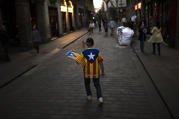 A man waves &quot;esteladas&quot;, or Catalonia independence flag, as he walks in downtown Barcelona, Spain, Monday Oct. 30, 2017. Catalonia&#039;s civil servants face their first full work week since ...