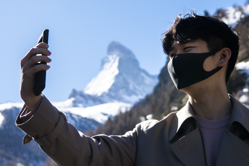 A tourist from South Korea poses as he takes a selfie in front of Matterhorn mountain in the ski resort, in Zermatt, Switzerland, Wednesday, March 18, 2020. The Swiss authorities proclaimed on 16 Marc ...