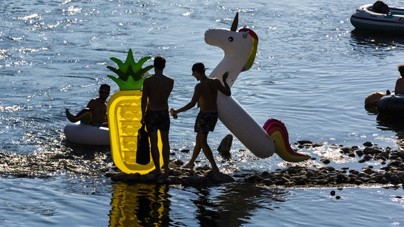 Cooling down at high summer temperatures - bathers enjoy their free time at the river Limmat with an pineapple airmattress and unicorn bathing ring, in Wipkingen, Zurich, Switzerland, on July 25, 2018 ...