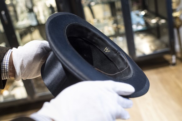 CORRECTS CITY TO GRASBRUNN -- A man holds a hat with the initials of Adolf Hitler prior to an auction in Grasbrunn, Germany, Wednesday, Nov. 201, 2019. A Jewish group has sharply condemned an auction  ...