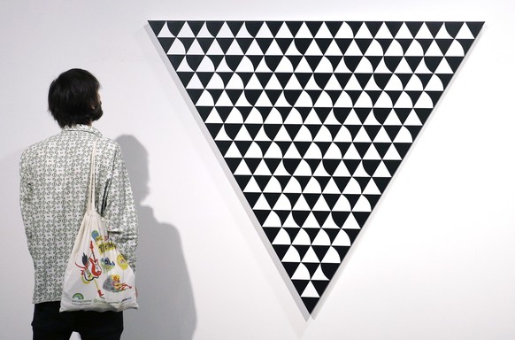 epa07215743 An Art Basel patron looks at &#039;Light Shade 7&#039; by Bridget Riley during Art Basel in Miami, Florida, USA, 07 December 2018. Art Basel represents over 250 art galleries onsite at the ...