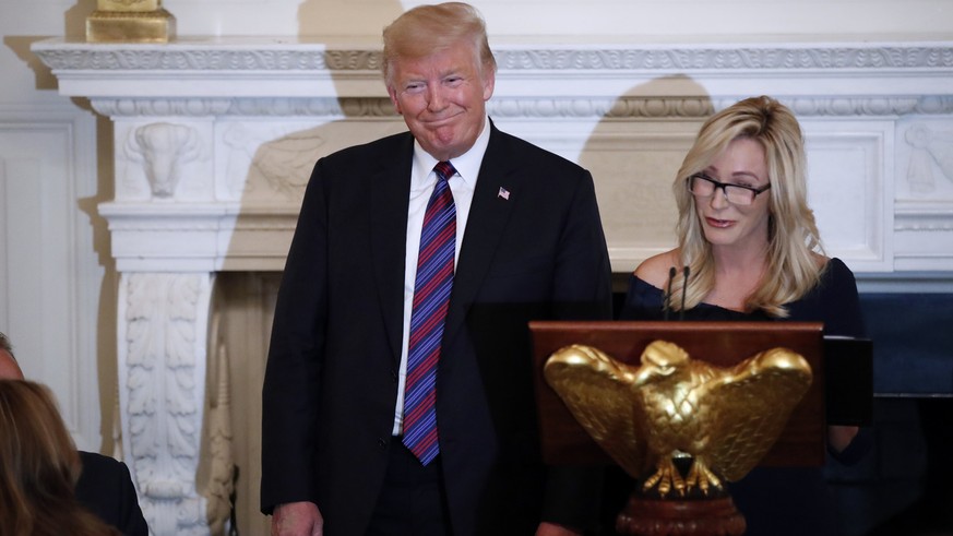 FILE - In this Aug. 27, 2018 file photo, President Donald Trump smiles as pastor Paula White prepares to lead the room in prayer, during a dinner for evangelical leaders in the State Dining Room of th ...
