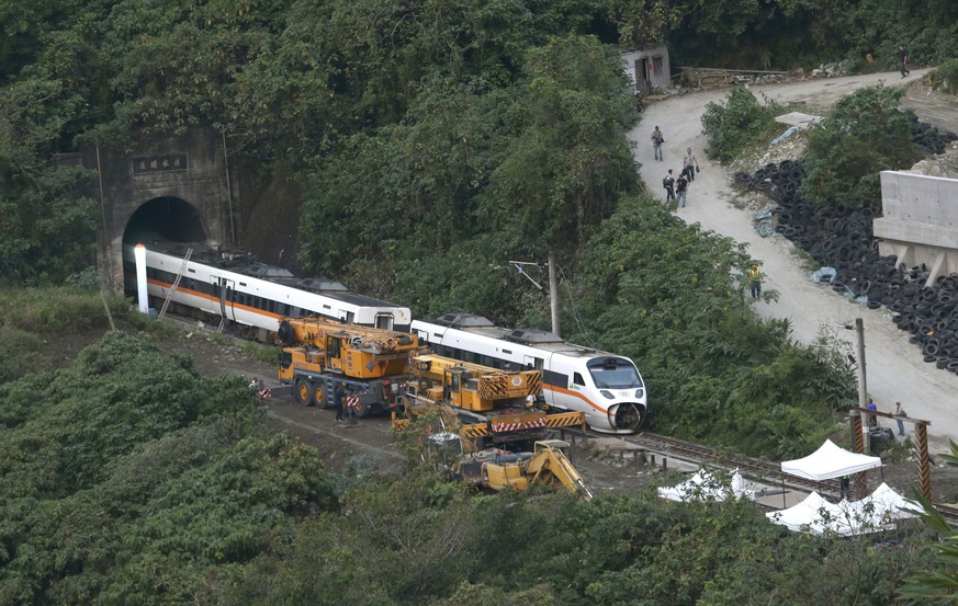 Rescue workers remove a part of the derailed train near Taroko Gorge in Hualien, Taiwan on Saturday, April 3, 2021. The train partially derailed in eastern Taiwan on Friday after colliding with an unm ...