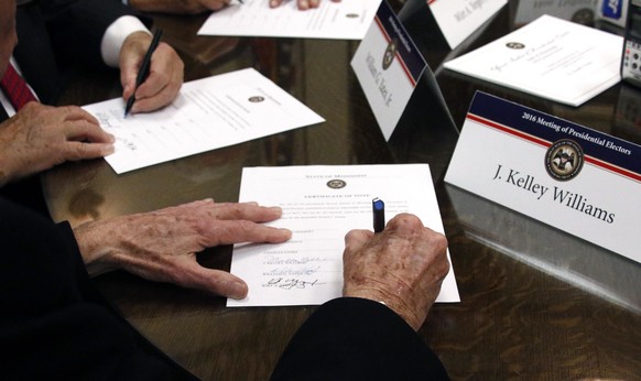 FILE - In this Dec. 19, 2016, file photo members of the Mississippi Electoral College sign certificates of vote in the process of formally casting their electoral votes in the 2016 General Election fo ...