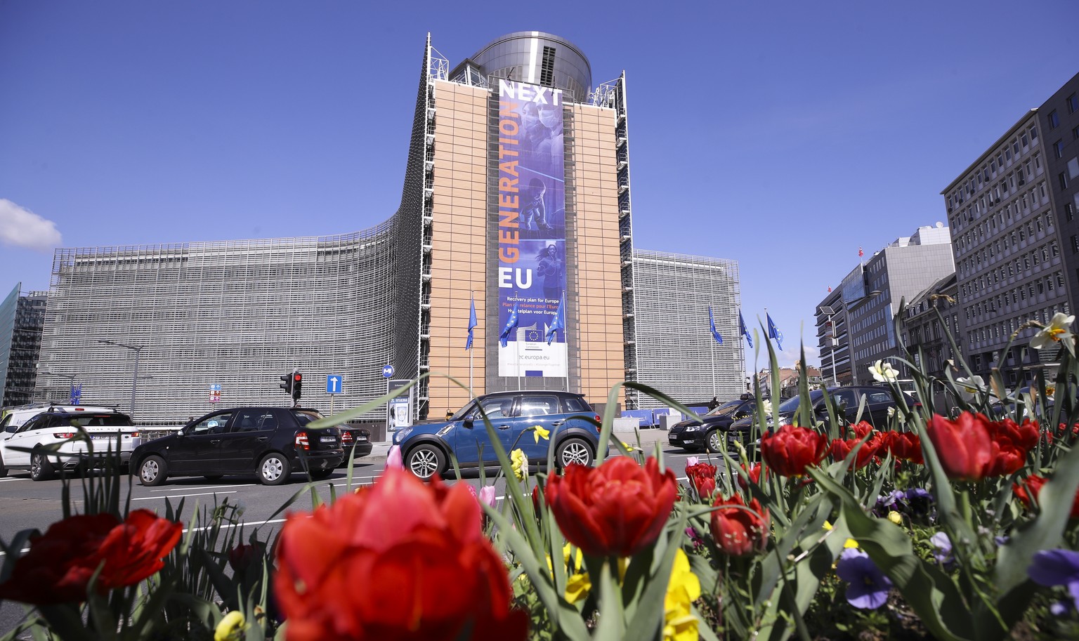 epa09139101 Blooming flowers obscure the view of cars queuing in front of Berlaymont Building, the European Commission headquarters in the European district of Brussels, 16 April 2021. EPA/OLIVIER HOS ...