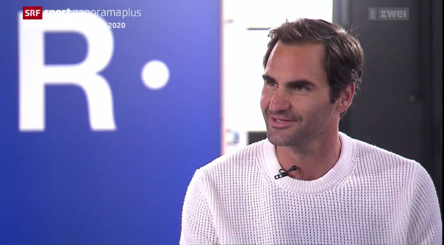 Federer im SRF-Interview – hinter ihm gross das Logo seines Schuhs.