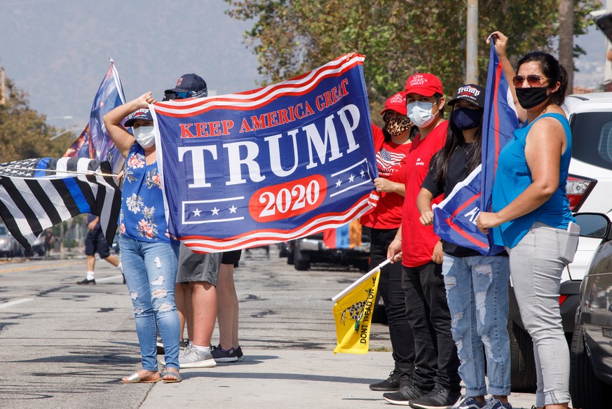 epa08721328 Supporters of US President Donald J. Trump wear masks as they wave a banner in Glendale, California, USA, 04 October 2020. Trump continues to recover at the Walter Reed Medical Center hosp ...
