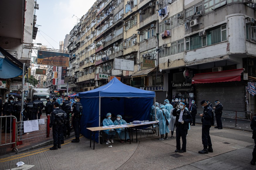 epa08959126 Civil servants in protective face masks and gowns enforce a lockdown in Jordan, Hong Kong, China, 23 January 2021. The Hong Kong government placed around 10,000 residents in an estimated 2 ...