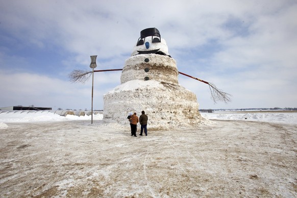 A couple and a child look at a 50-foot snowman named &quot;Granddaddy&quot; in Gilman, Minnesota, March 6, 2014. The snowman began to take shape earlier this winter when farmer Greg Novak needed to mo ...