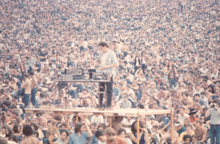 A sound guy stands on scaffolding with his equipment in front of the crowd at the Woodstock music festival, August 1969. (Photo by Ralph Ackerman/Getty Images)