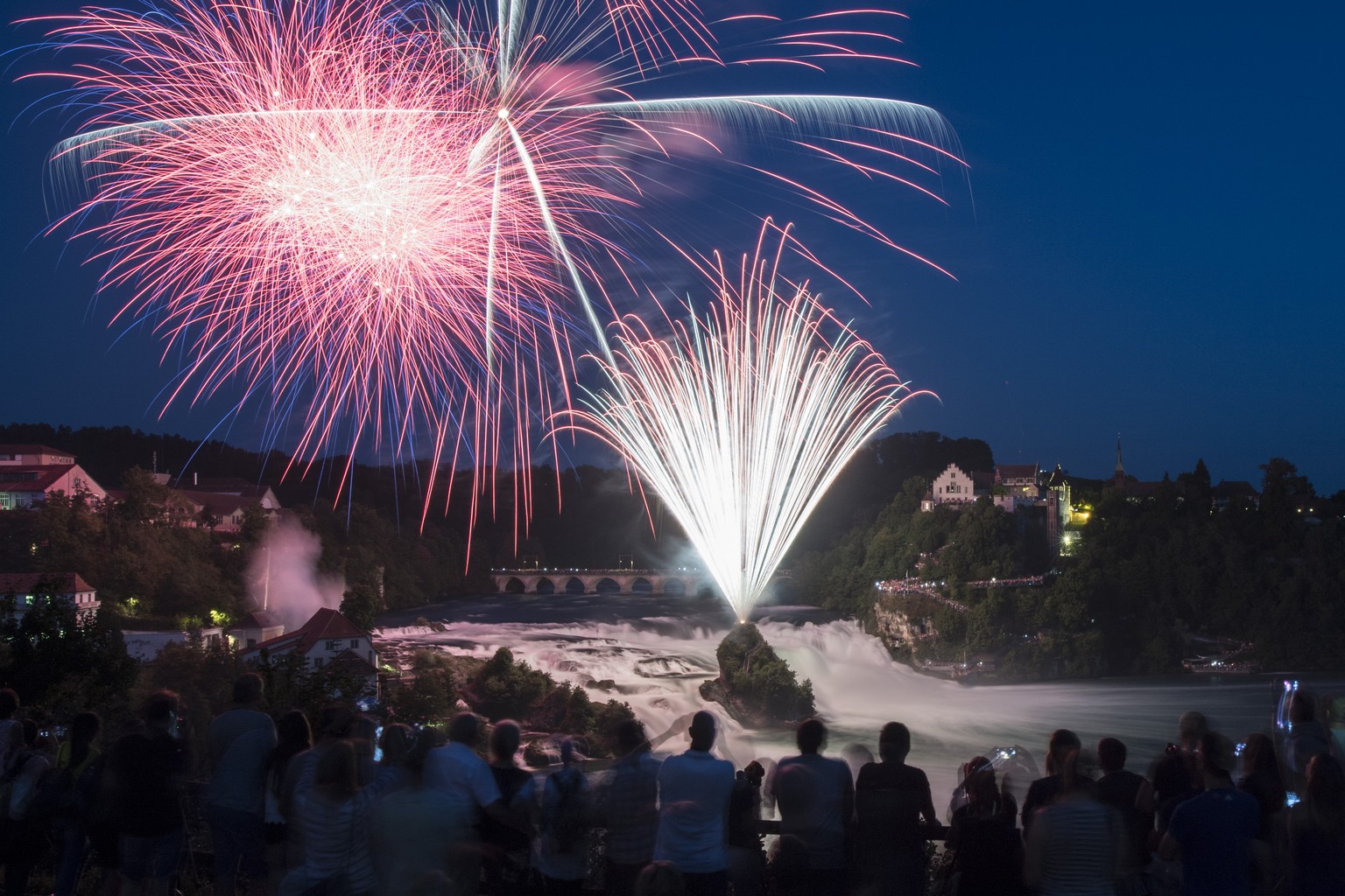 Menschen betrachten das Feuerwerk &quot;Fire on the rocks&quot; am Himmel ueber dem Rheinfall, anlaesslich des Nationalfeiertags am ersten August, aufgenommen am Montag, 31. Juli 2017 in Neuhausen am  ...