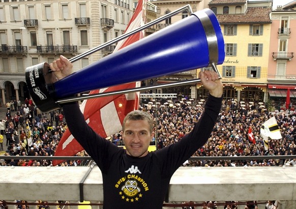 Sandro Bertaggia stemmt den Meisterpokal in die Hoehe am Freitag, 11. April 2003, auf der Terrasse des Luganeser Rathauses mit der vollen Piazza Riforma im Hintergrund. Der HC Lugano ist im Rahmen der ...
