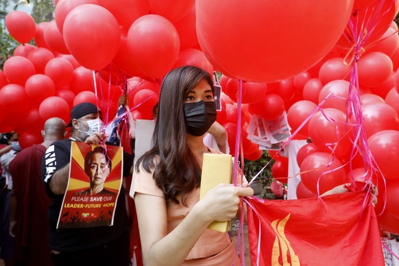 epaselect epa09092685 Protesters hold placards and a flag of the National League for Democracy (NLD) party attached to red balloons during a protest against the military coup, in Yangon, Myanmar, 24 M ...