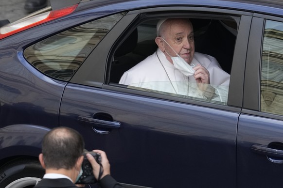 Pope Francis takes out his face mask as he arrives for his weekly general audience with a limited number of faithful in the San Damaso Courtyard at the Vatican, Wednesday, June 2, 2021. (AP Photo/Andr ...
