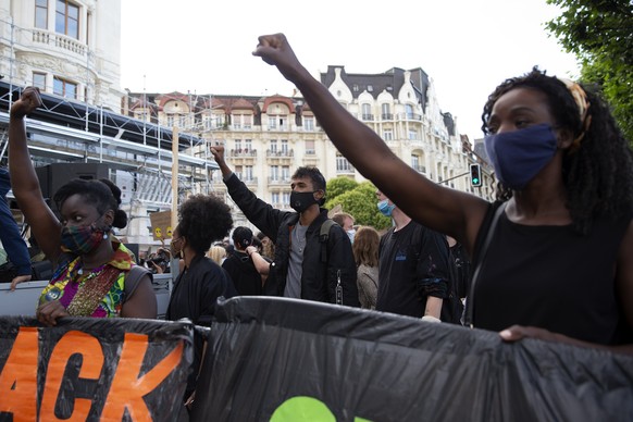 epa08525633 Demonstrators raise their fist as they take part in an anti-racism demonstration, against police violence, during a Black Lives Matter (BLM) protest, in Geneva, Switzerland, 03 July 2020.  ...