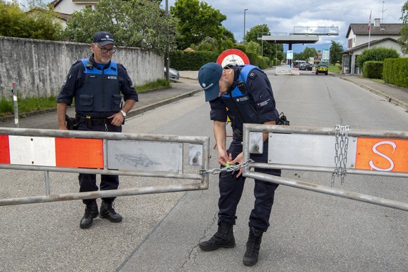 Two border guards opens the barrier that closed access to customs, in Thonex near Geneva, Switzerland, on Sunday, June 14, 2020. Concrete blocks closed the road at the Swiss-French border during the s ...