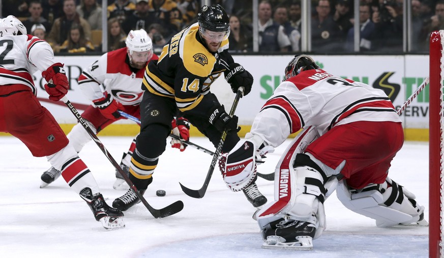 The puck slides behind Boston Bruins&#039; Chris Wagner (14) as he closes in on Carolina Hurricanes goaltender Petr Mrazek, right, of the Czech Republic, during the second period in Game 2 of the NHL  ...