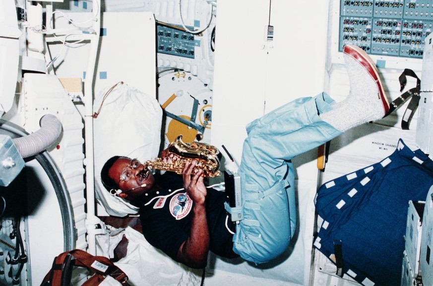 February 1984: Mission specialist Ronald McNair relaxes with his saxophone during the STS 41-B mission on the Challenger shuttle. Zero gravity allows him to float around while playing his instrument.  ...