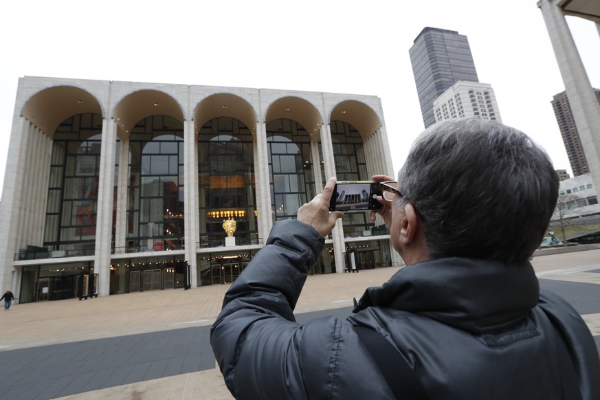 Denis Guidone pauses to take a photograph in front of the Metropolitan Opera House at Lincoln Center on Thursday, March 12, 2020, in New York. The Met Opera canceled performances and rehearsals throug ...
