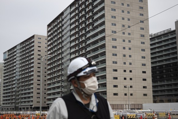 A worker walks through the athletes&#039; village for the Tokyo 2020 Olympics, in Tokyo, Monday, March 23, 2020. The IOC will take up to four weeks to consider postponing the Tokyo Olympics amid mount ...