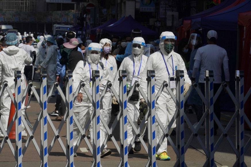 Government workers wearing personal protective equipment walk at the closed area in Jordan district in Hong Kong, Saturday, Jan. 23, 2021. Thousands of Hong Kong residents were locked down Saturday in ...