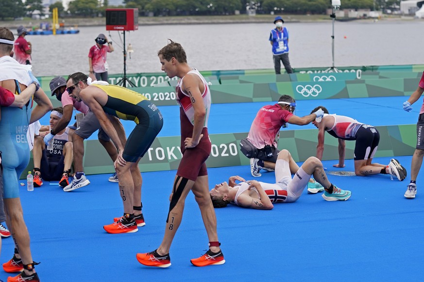 Exhausted athletes lie on the ground, including Kevin McDowell of the United States, left, Casper Stornes of Norway (45), Jonathan Brownlee of Great Britain (54) after finishing the men&#039;s individ ...