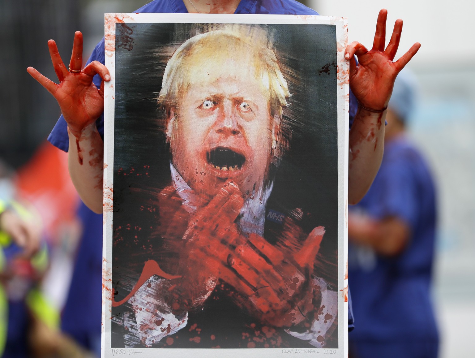A nurse holds a painting of Prime Minister Boris Johnson clapping with blood on his hands as part of a demonstration of NHS workers at hospitals across London to demand a 15 per cent pay rise by the g ...