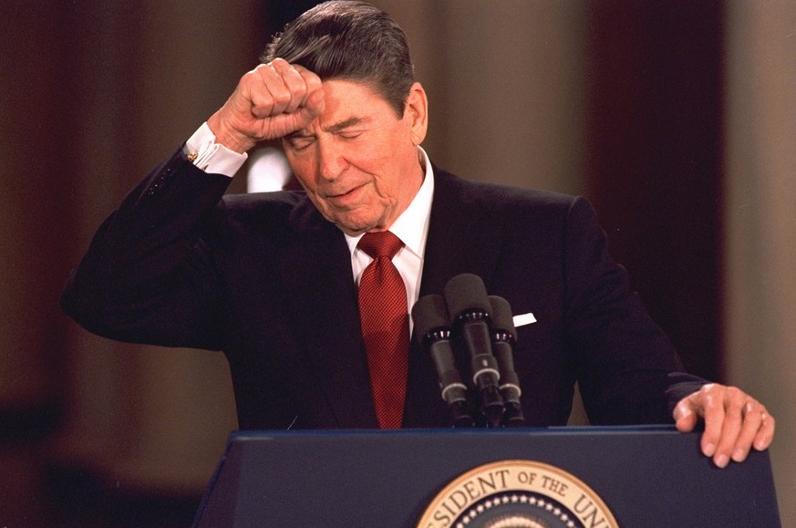 FILE - In this March 19, 1987 file photo, President Ronald Reagan taps his forehead at the White House while responding to a reporter&#039;s question during a news conference at which he said he never ...