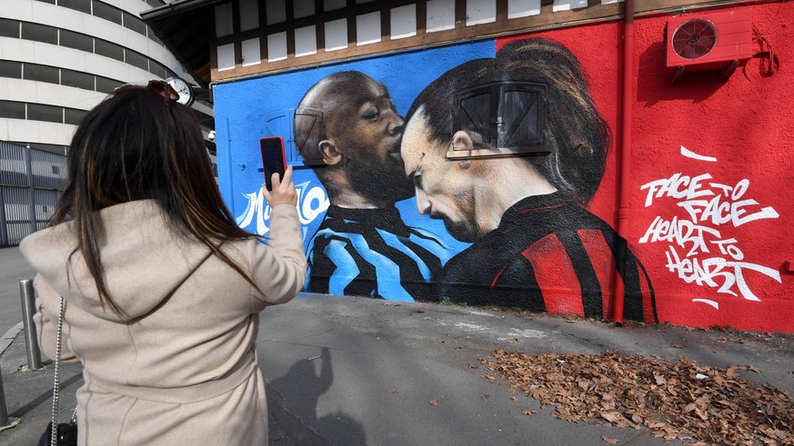 epa09014661 A woman takes a photo of a mural near the Giuseppe Meazza Stadium, depicting Inter Milan&#039;s Romelu Lukaku (L) and AC Milan&#039;s Zlatan Ibrahimovic head to head arguing during an Ital ...