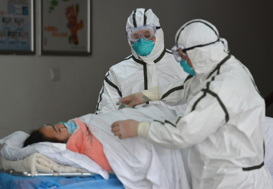 epa08183670 Two specialized transport staff take care of a patient, infected with novel coronavirus, who was sent to the Second People&#039;s Hospital, which was designated to handle patients of the n ...