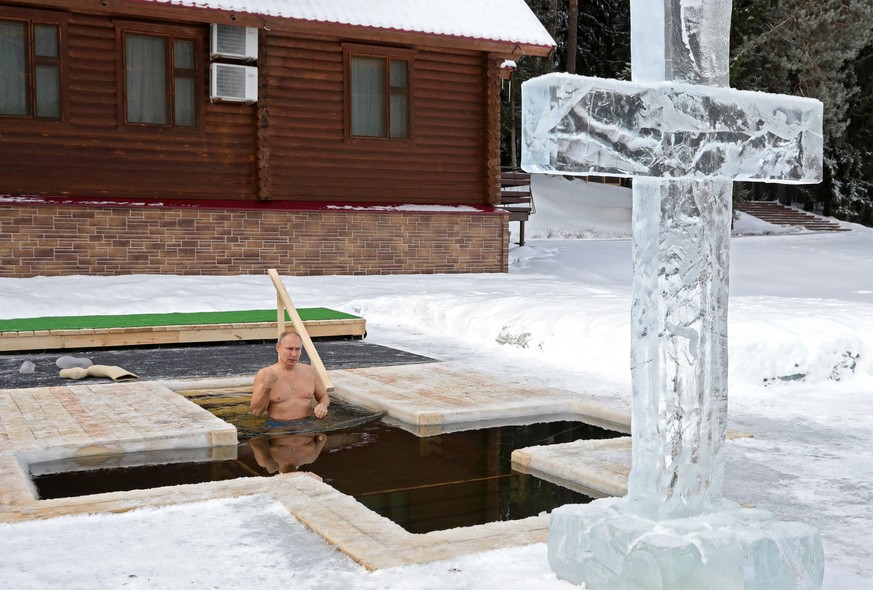 Russian President Vladimir Putin crosses himself while bathing in the icy water during a traditional Epiphany celebration as the temperature dropped to about -20 degrees (-4 degrees Fahrenheit) outsid ...