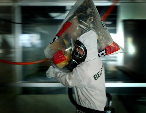 Ein Arbeiter mit Atemschutz und Schutzkleidung traegt einen Plastiksack voll asbestverseuchtem Restmaterial, aufgenommen am Dienstag, 25. Februar 2003, im Werd Hochhaus in Zuerich. Das Werd Hochhaus w ...