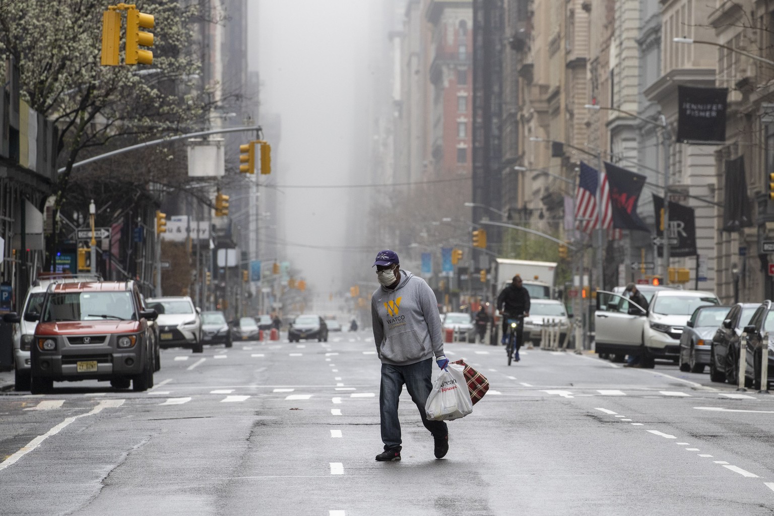A man wearing a facial mask walks across the middle of 5th Avenue in Midtown Manhattan of New York, Sunday, March 29, 2020. (AP Photo/Mary Altaffer)
