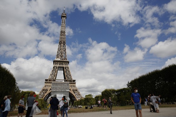 People take a break next to the Eiffel Tower in Paris, Sunday, July 26, 2020. France&#039;s coronavirus infection rate has continued its worrisome upward creep, with health authorities saying each inf ...
