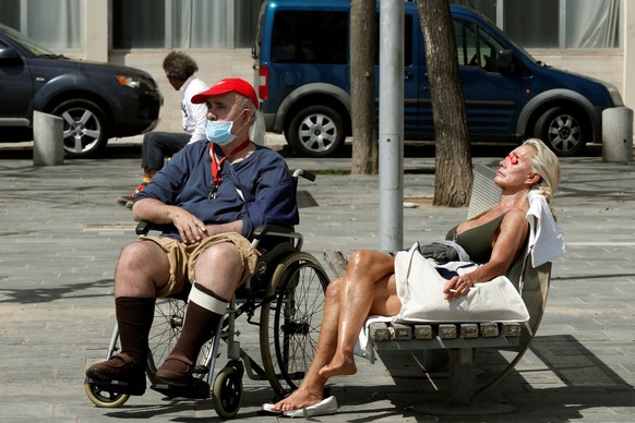 epa08405474 A couple enjoys the sun on a street in Barcelona, Catalonia, northeastern Spain, 06 May 2020. Spain is carrying out the de-escalation phase at different speeds depending on health situatio ...