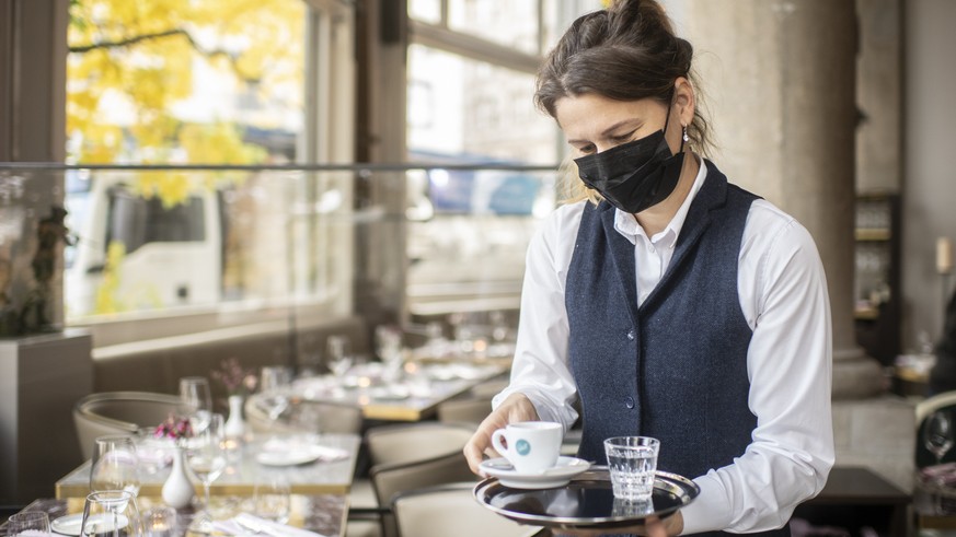 Eine Frau mit Atemschutzmaske serviert einen Espresso im Restaurant Terrasse, aufgenommen am Dienstag, 27. Oktober 2020 in Zuerich. (KEYSTONE/Ennio Leanza)