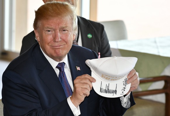 epa06309204 US President Donald J. Trump shows off a signed hat reading &#039;Donald and Shinzo, Make Alliance Even Greater&#039; at the Kasumigaseki Country Club in Kawagoe, Japan, 05 November 2017.  ...