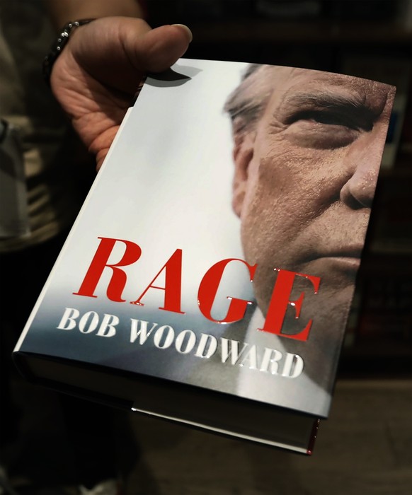 epa08671693 An employee at Shakespeare &amp; Co. holds out the new book by Bob Woodward &#039;Rage&#039;, in New York, New York, USA, 15 September 2020. The book is released after recordings during in ...