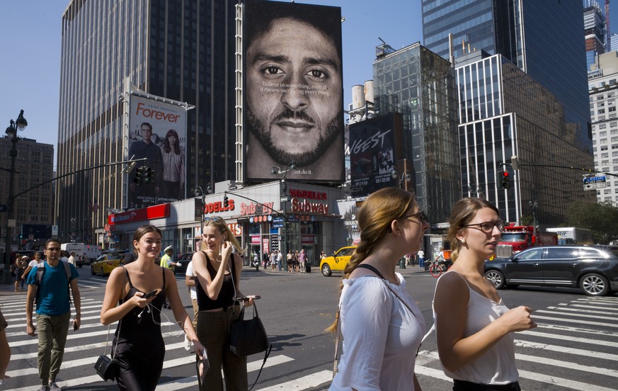 FILE - In this Sept. 6, 2018, file photo, people in New York walk past a Nike advertisement featuring former San Francisco 49ers quarterback Colin Kaepernick, known for kneeling during the national an ...