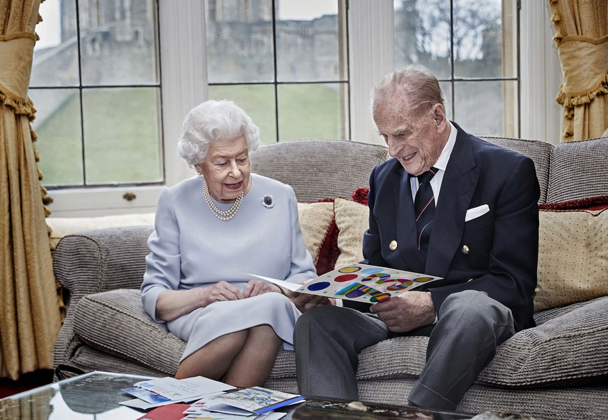 In this image released on Thursday Nov. 19, 2020, Britain&#039;s Queen Elizabeth II and Prince Philip, Duke of Edinburgh look at a homemade wedding anniversary card, given to them by their great grand ...