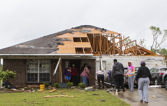 Neighbors and family help to clean a damaged home in Monroe, La. after a tornado ripped through the town just before noon on Sunday, April 12, 2020. (Nicolas Galindo/The News-Star via AP)