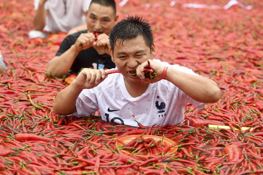 epa06873870 A contestant reacts during a chili-eating contest in a pool of chilies in Ningxiang city in south China&#039;s Hunan province, 08 July 2018. Local citizen Tang Shuaihui swallowed 50 chilie ...