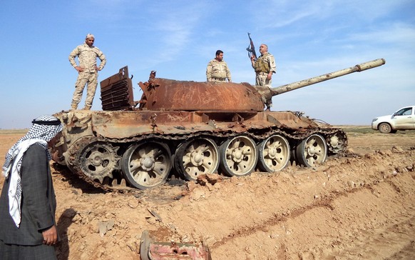 epa04635731 Iraqi soldiers stand on a damaged tank during fighting against IS militants near Tikrit, northern Iraq, 24 February 2015. Iraqi troops broke a siege by Islamic State militants on a residen ...