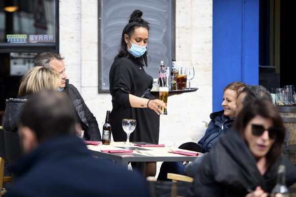 A waitress wearing a face protection mask serves lunch on the terrace of the &quot;L&#039;Etoile Blanche&quot; the opening day of the terrace, restaurants can only open their terraces but indoor rooms ...