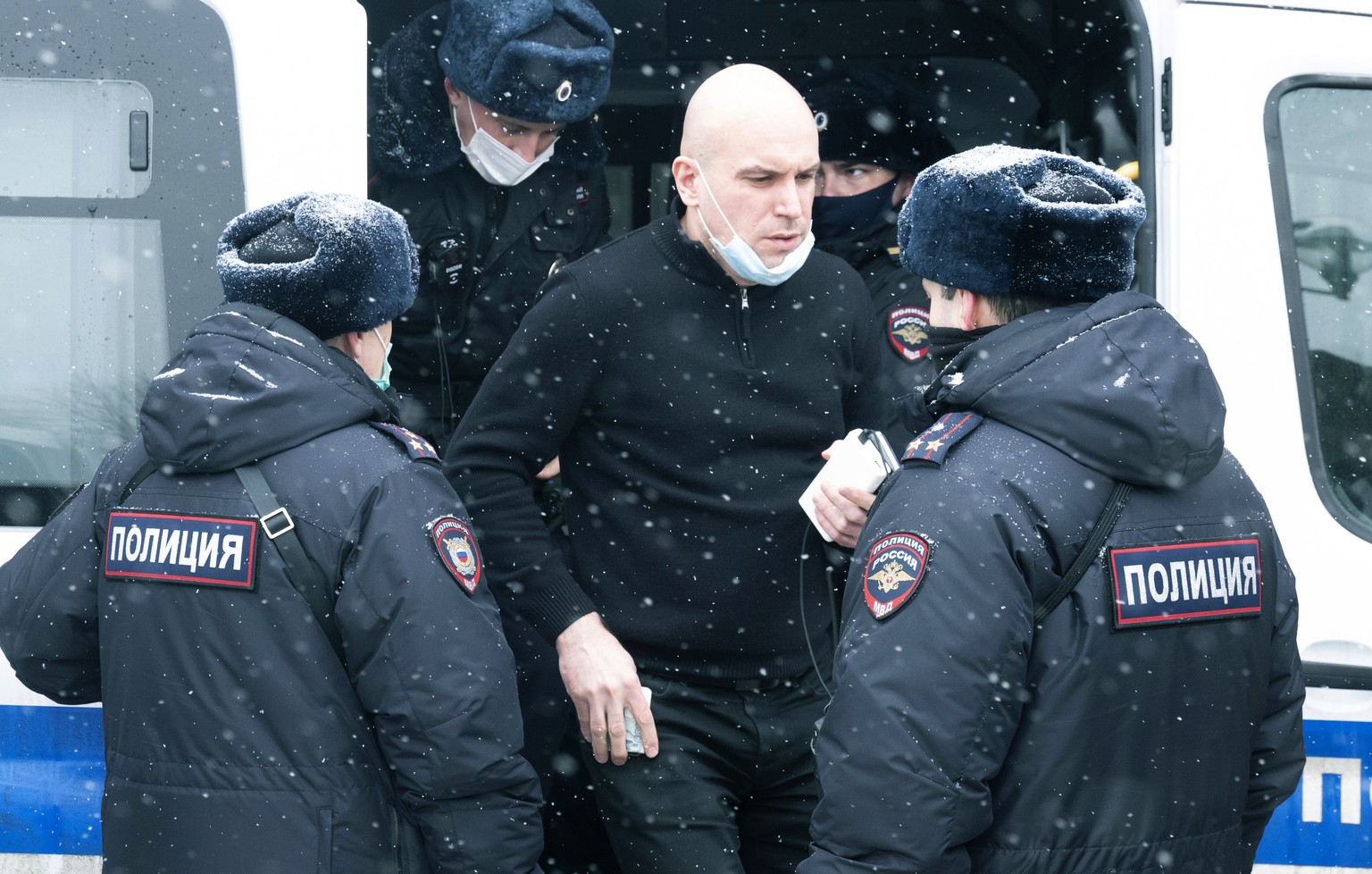 A man stands near a police bus after he was detained in Moscow, Russia, Saturday, March 13, 2021. Russian police on Saturday detained about 150 participants of a forum of independent members of munici ...