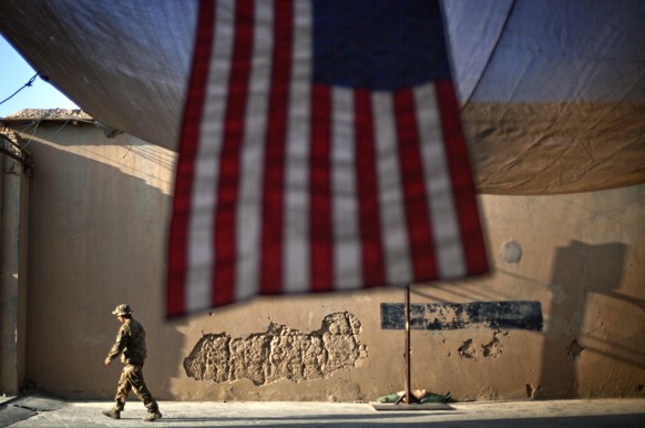 FILE - In this Sept. 11, 2011 file photo, A U.S. Army soldier with the 25th Infantry Division, 3rd Brigade Combat Team, 2nd Battalion 27th Infantry Regiment walks past an American Flag hanging in prep ...