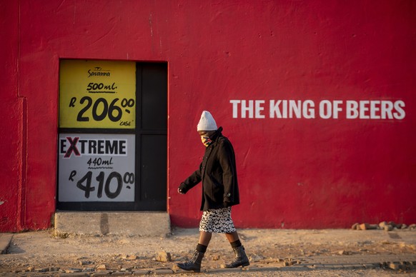 A woman walks in front of a closed alcohol shop in the township of Soweto outside of Johannesburg, South Africa, Monday, July 13, 2020, The sale of alcohol been banned since the country went into a st ...